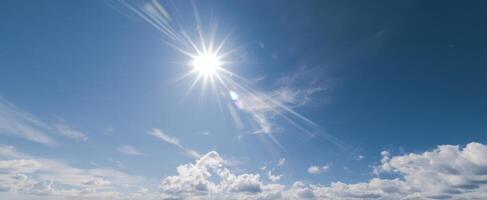 The radiant sun shining over a clear blue sky with fluffy clouds. photo