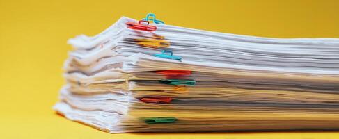 The stack of organized papers with color-coded clips against a yellow background photo