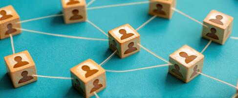The interconnected network of people represented by wooden cubes on a blue background. photo