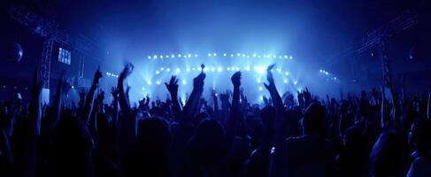 The crowd enjoying a vibrant concert under dazzling blue lights. photo