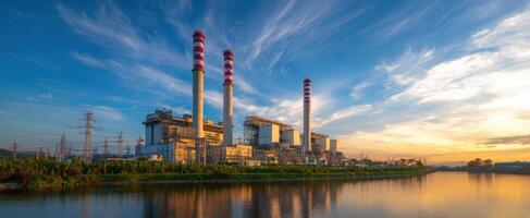The power plant reflecting the vibrant sunset over the tranquil riverbank. photo