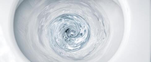 The swirling water inside a modern toilet bowl creating dynamic motion photo