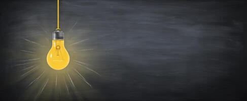 The illuminated yellow bulb hanging against a chalkboard background. photo