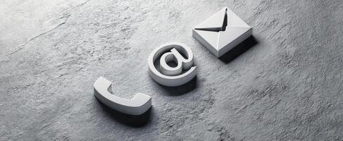 The digital communication symbols of phone, email, and at sign on a surface. photo