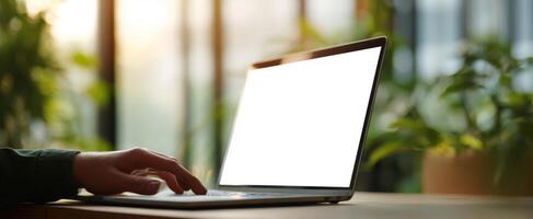 The modern laptop in a sunlit workspace surrounded by lush greenery. photo