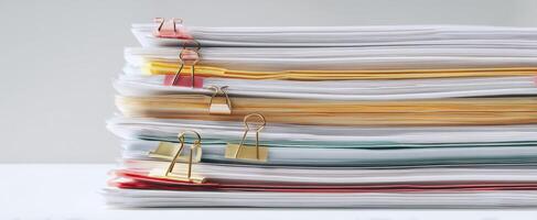 The organized stack of documents with colorful binder clips on a clean surface. photo