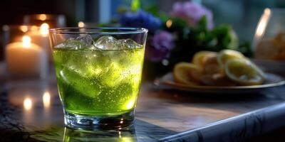 Refreshing green drink with ice served on a marble table during a cozy evening gathering photo