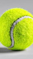 Bright green tennis ball with detailed texture and stitching displayed on a neutral background photo