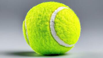 Bright yellow tennis ball positioned against a neutral background highlighting its texture and vivid color photo