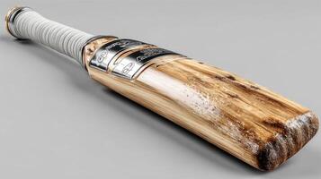 Vintage cricket bat resting on a smooth surface with signs of wear, showcasing craftsmanship and history photo