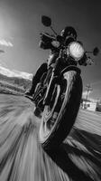 Motorcyclist riding fast along a rural road during a clear sunny day with mountains in the background photo