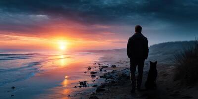 Man and dog enjoy a serene sunset stroll along the beach with vibrant colors reflecting on the water photo