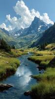 Majestic mountain landscape with a serene stream flowing through lush green fields in a picturesque valley under a blue sky photo