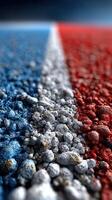 Colorful texture of gravel painted in red, white, and blue stripes on a surface in bright daylight photo