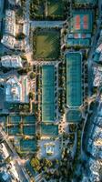 Aerial view of tennis courts surrounded by greenery and urban structures in a city park during early morning light photo