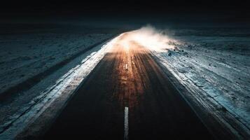 Nighttime view of a deserted road with fog and steam rising on the icy surface in a remote location photo