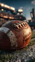 Close-up of a weathered football resting on the field during sunset at a stadium photo