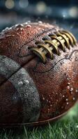 Football resting on wet grass during a rainy game, showcasing texture and detail of the ball and droplets photo