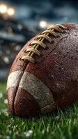 Close-up view of a weathered football resting on grass under soft evening light photo