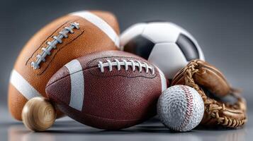 Various sports balls arranged on a surface, including footballs, soccer ball, baseball, and glove for an engaging sports display photo