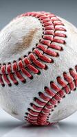 Baseball resting on a smooth surface showing signs of wear and tear with intricate stitching details in close-up photo