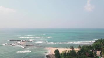 Aerial view crowded beach in Tangalle, Sri Lanka, where tourists enjoy swimming and sunbathing along the tropical coastline. A lively vacation scene with turquoise waves and palm-lined shores video