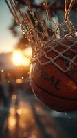Basketball effortlessly swishes through the net at sunset during an outdoor game photo