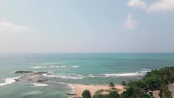 Aerial panorama view crowded beach in Tangalle, Sri Lanka, where tourists enjoy swimming and sunbathing along the tropical coastline. A lively vacation scene with turquoise waves and palm-lined shores video