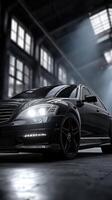 Sleek black luxury car parked in a dimly lit industrial warehouse with dramatic lighting photo
