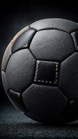 Detailed close-up of a black soccer ball resting on a dark surface highlighting its texture and craftsmanship photo