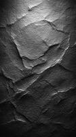 Textured black stone surface with distinct layers and shadows in natural lighting photo
