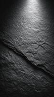 Textured dark stone surface illuminated by soft light highlighting its natural pattern photo