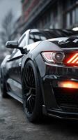 Dark sports car parked on a rainy street at dusk showcasing sleek design and vibrant headlights photo