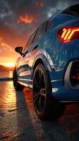 Golden sunset reflects off a blue car parked by the water near the shoreline in the evening photo
