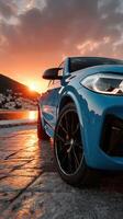 Modern blue SUV parked near the coastline during sunset, showcasing its sleek design and reflective surface against the vibrant sky photo