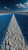 Expansive blue salt flat under a vibrant sky with captivating clouds near a distant mountain range photo