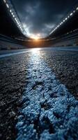 Sunset over an empty sports stadium showcasing a blue racing lane and dramatic clouds photo
