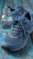 Blue athletic shoe with water bottle on wooden table, showcasing active lifestyle and hydration photo