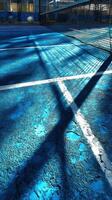 Shadows create abstract patterns on a blue tennis court during a sunny afternoon at a local sports center photo