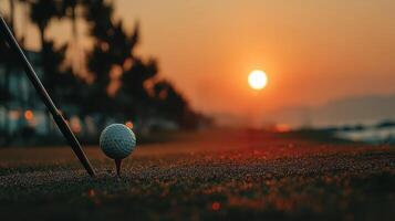 Golf ball ready for swing at sunset on the green with horizon glowing in warm colors photo