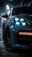 Close-up view of a sleek blue sports car with illuminated headlights in a dimly lit garage photo