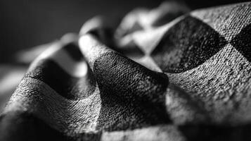 Textured black and white fabric with a checkered pattern displaying intricate folds and shadows in natural light photo