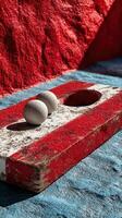 Two spherical objects resting on a weathered painted board in a vibrant outdoor setting showing red and blue hues photo