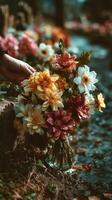 Hand placing a vibrant bouquet of flowers by the water in a serene outdoor setting during late afternoon photo
