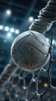 Close-up view of a worn soccer ball lodged in the goal net during an evening match in a stadium photo
