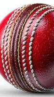 Red cricket ball lying on a flat surface with detailed stitching visible and vibrant color in bright lighting photo
