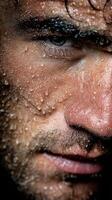 Close-up of a man with water droplets on his face showcasing intense expression and details in a dramatic, moody setting photo