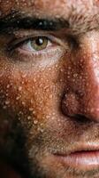 Close-up view of a man with water droplets on his face, emphasizing an intense expression and texture of skin photo