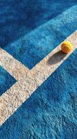 Tennis ball rests on blue court surface during sunny day, inviting play and fun activity for athletes and enthusiasts alike photo