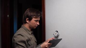Electrician installing light switch and using digital tablet video
